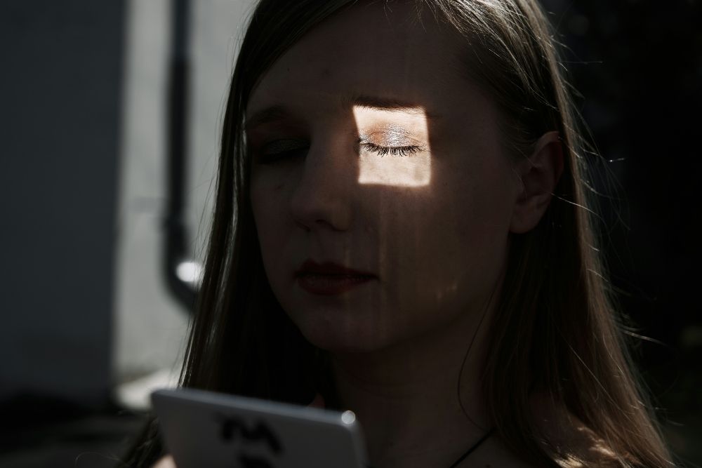 Rostro de una mujer iluminado por la pantalla de un móvil, con un recuadro de análisis facial superpuesto que simboliza una app de detección de deepfakes en acción